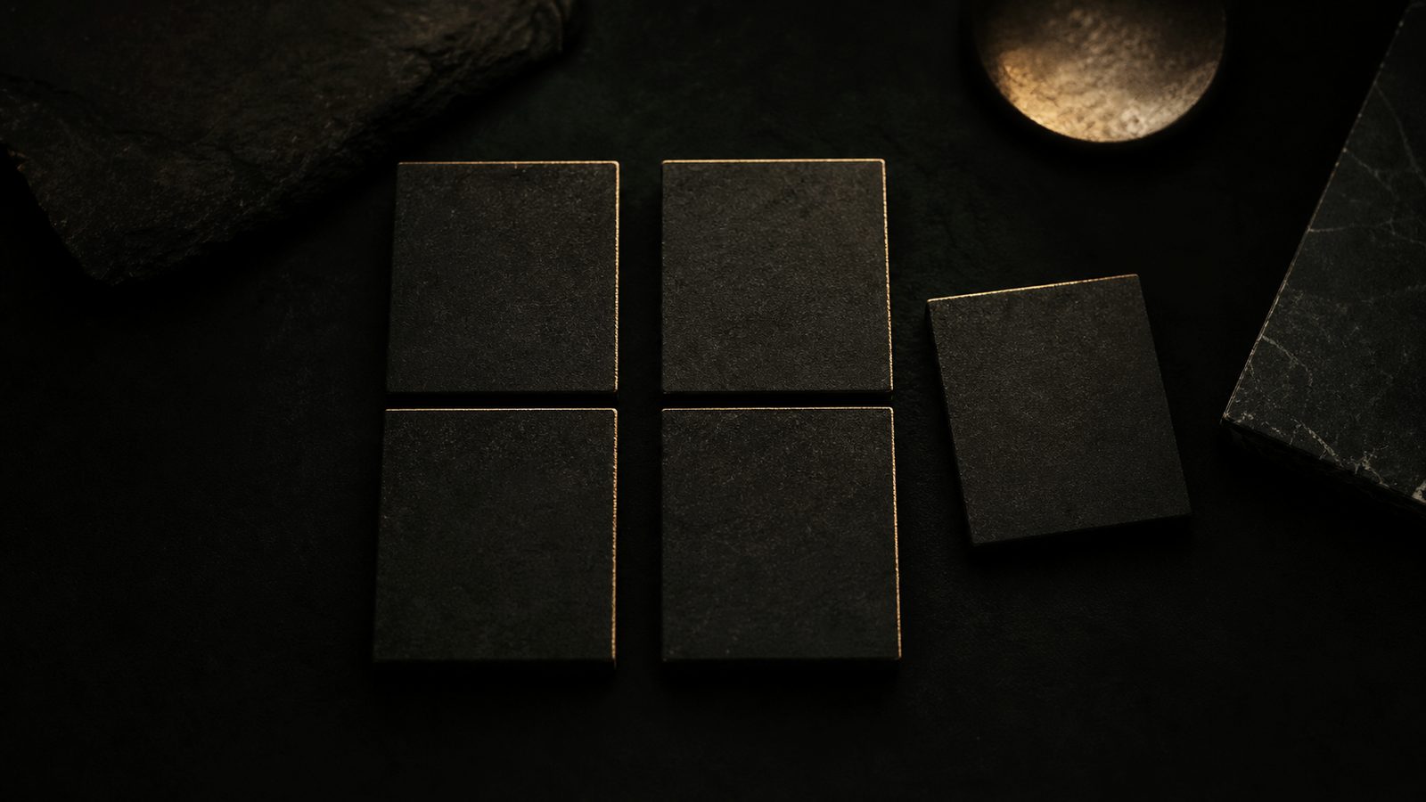 Five dark rectangular slabs arranged on a black stone surface